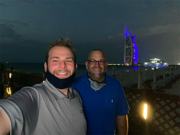 President Nathan Parvin smiling with his son, Joshua Parvin. The UAE cityscape is in the background.