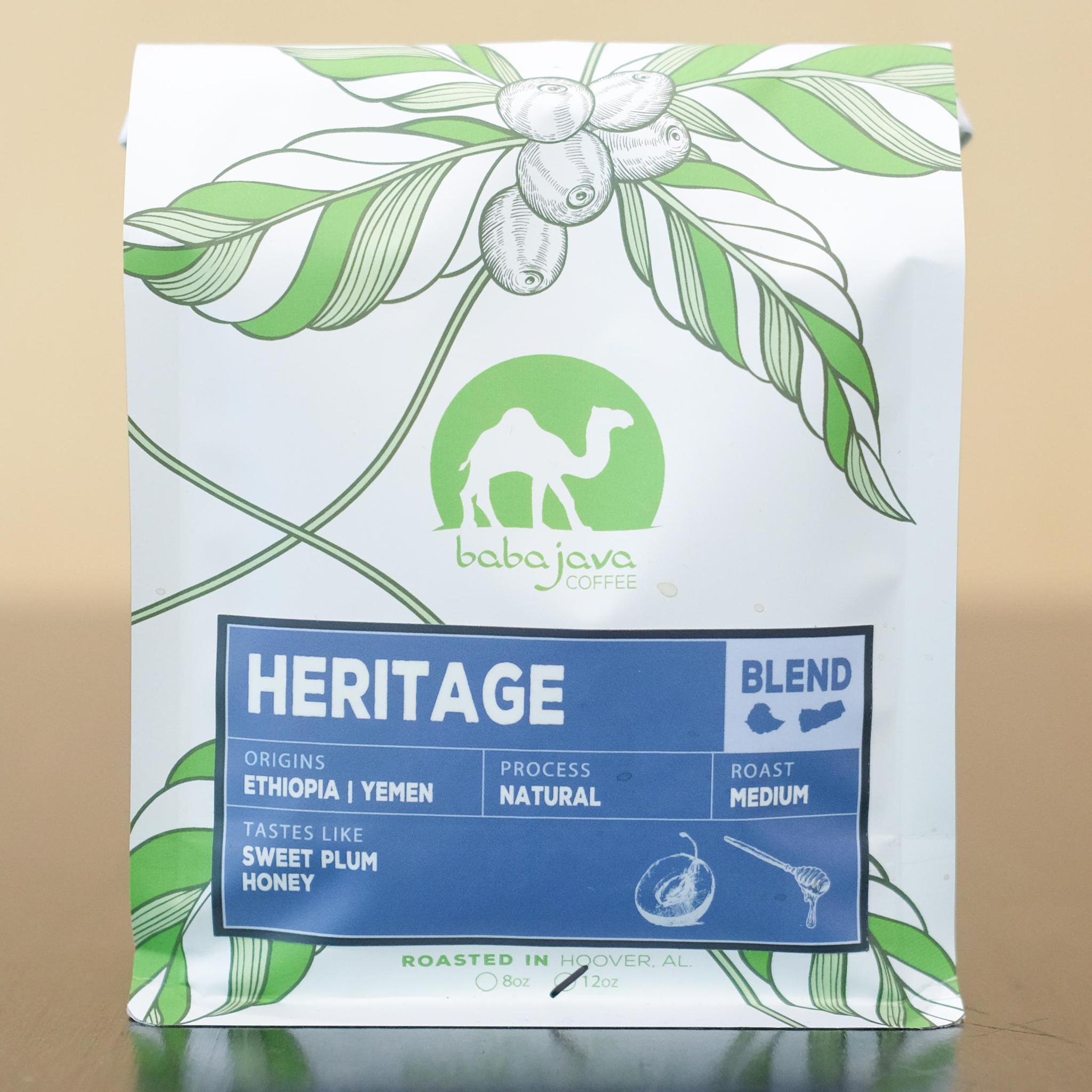 A bag of coffee with a blue label that reads Heritage Blend. The bag has a drawing of a coffee plant and the Baba Java Coffee logo.