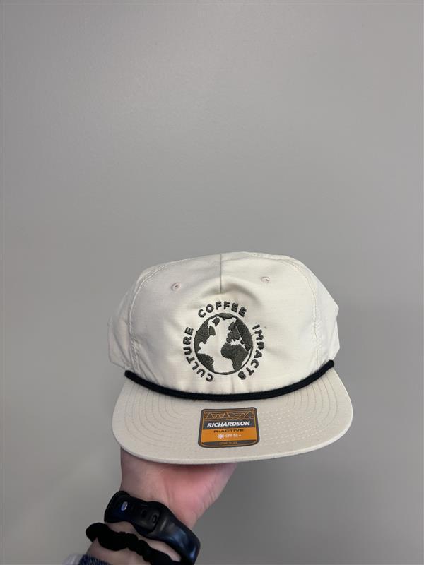 A cream colored hat with the words Coffee Impacts Culture in a circle around a picture of the Earth.